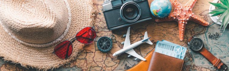 A hat, passport, plane tickets, and camera on top of a map